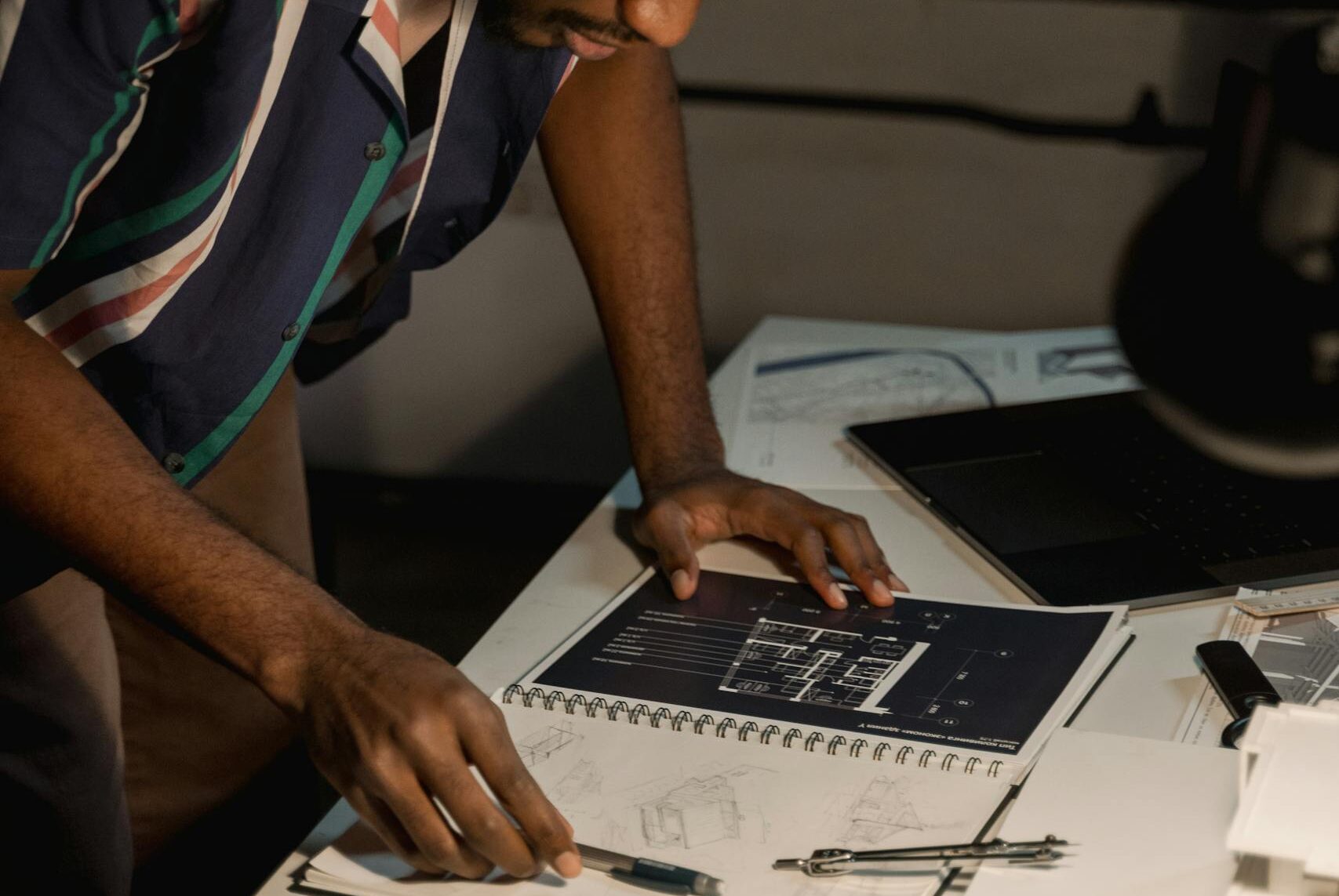An architect intensely reviewing detailed floor plans in an office setting.