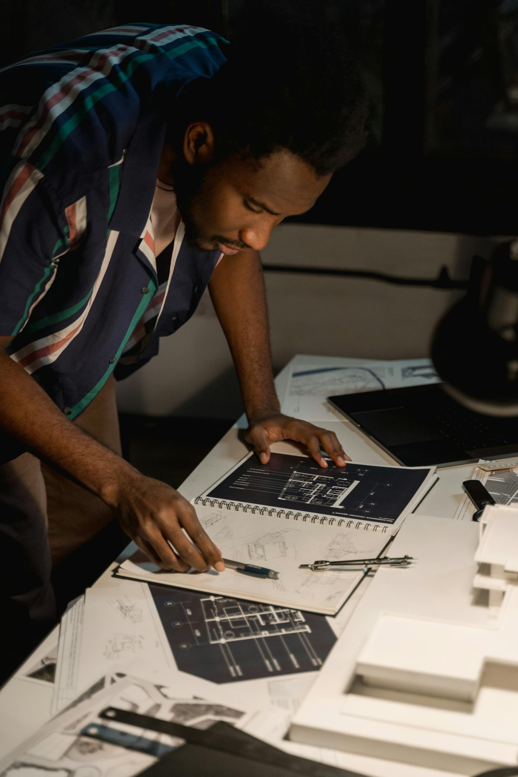 An architect intensely reviewing detailed floor plans in an office setting.